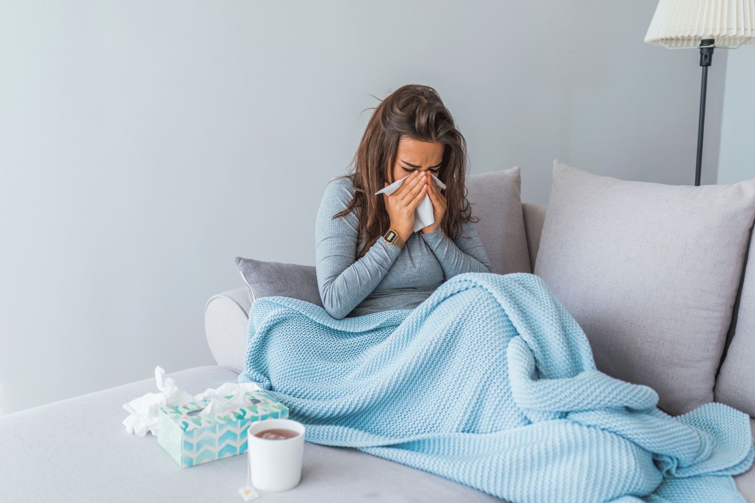 lady sick on the couch, blowing her nose