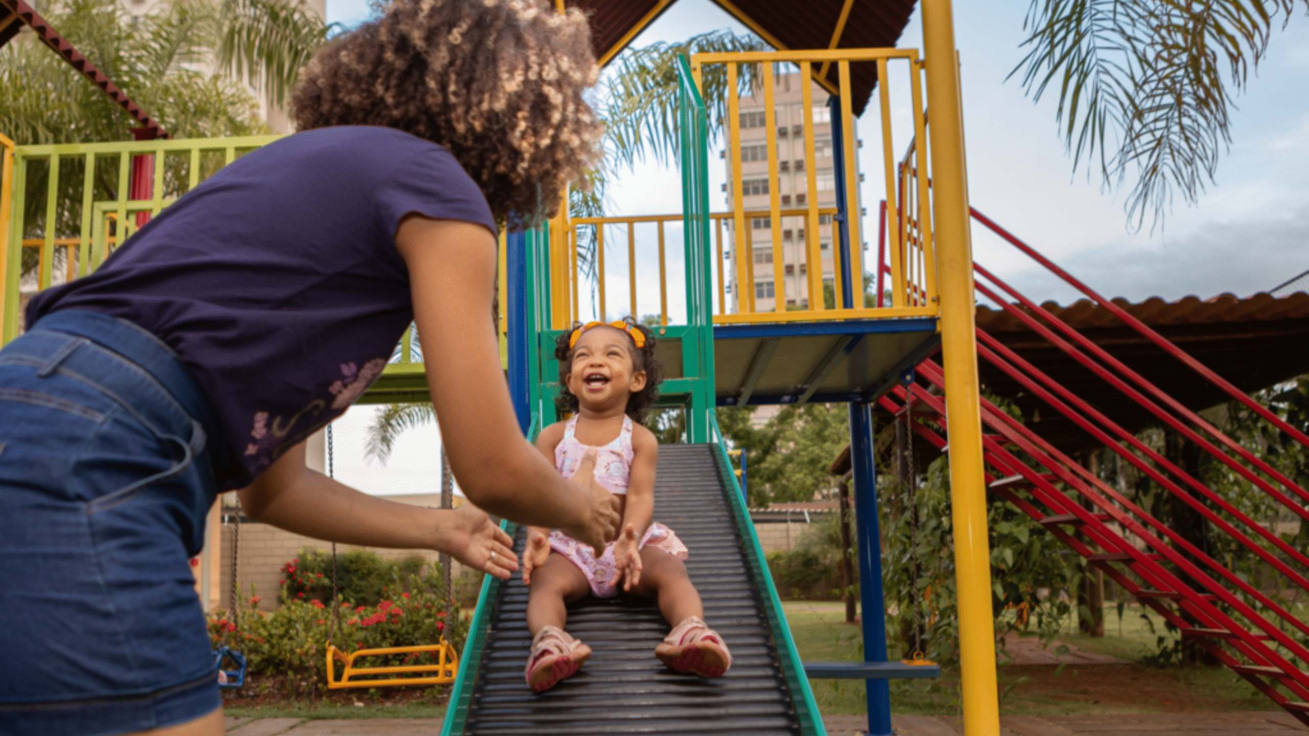 woman helping her child down the slide