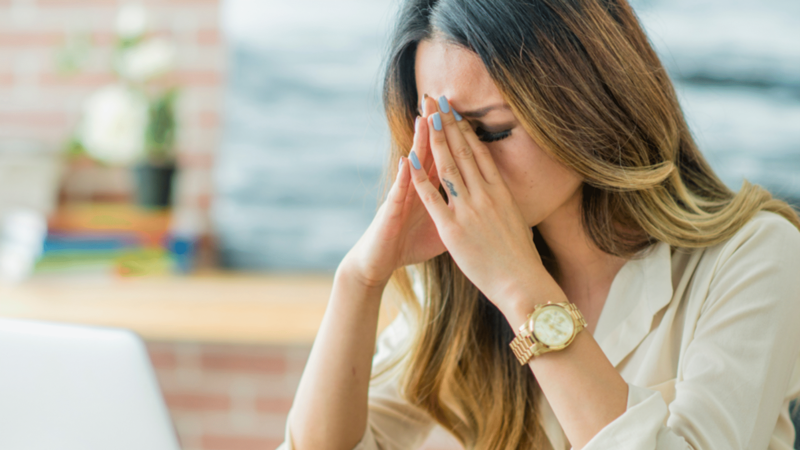 lady with built up stress puts hands on face and lays on desk