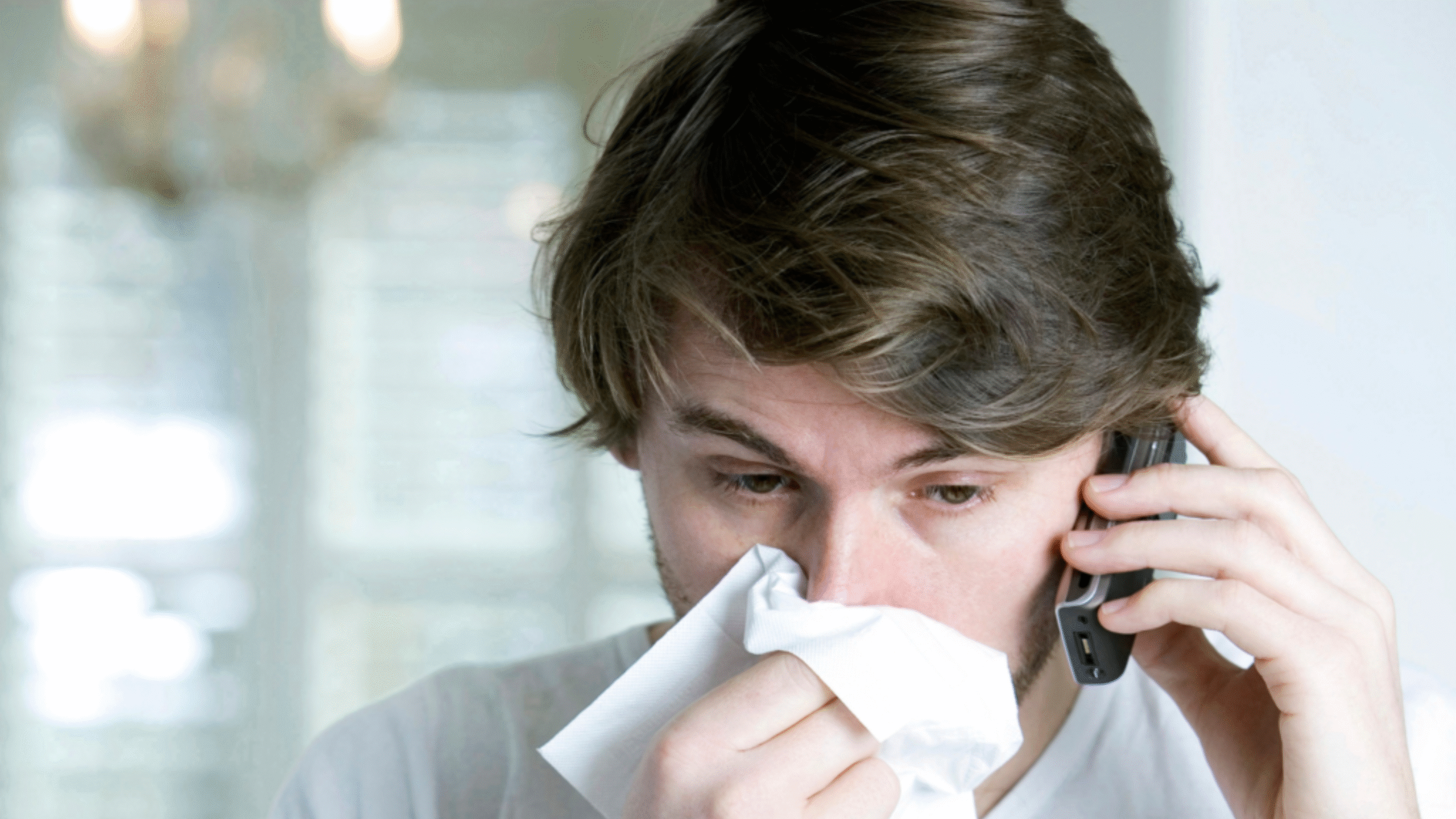 man blowing his nose while calling his doctor